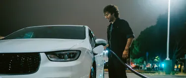 Ein Mann steht an seinem E-Fahrzeug und lädt es auf