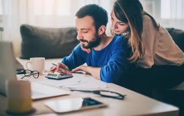 Ein Mann und eine Frau berechnen etwas mithilfe eines Taschenrechners