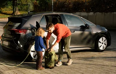 Ein Mann und ein Kind laden ein Elektroauto