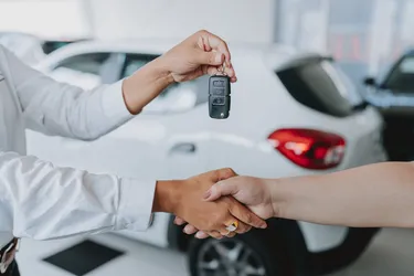 Eine Frau nimmt einen Autoschlüssel von einem Autohändler entgegen