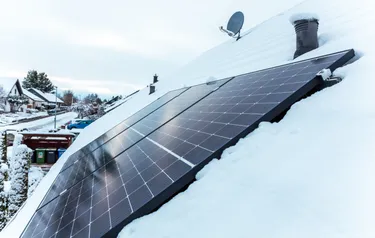 Nahaufnahme eines auf einem Hausdach montierten Solarpanels im Winter