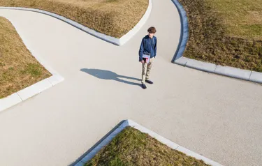 Ein junger Mann steht an einer sich in vier Wege gabelnden Kreuzung