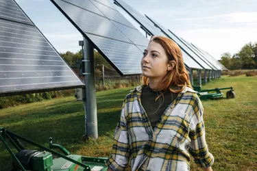Eine Frau steht neben den Solarpaneelen einer Freiflächen Photovoltaikanlage