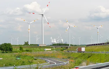 Ansicht einer Landschaft mit einer Landstraße im Vordergrund und Industrieanlagen im Hintergrund
