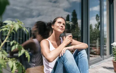 Eine Frau blickt lächelnd gen Sonne in den Himmel