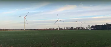 Drei Windräder auf einem grünen Feld