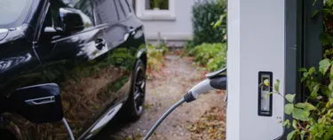 E-Auto an der E-Ladesäule vor einem Einfamilienhaus