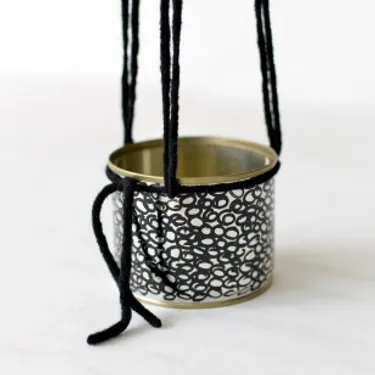 Schritt 4: Das Bild zeigt, wie die Wollstränge an den Dosen richtig verknotet werden, damit diese mittig hängen können.