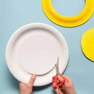 Schritt 1: Das Bild zeigt, wie Pappteller gelb bemalt und beschnitten werden. 