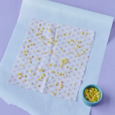 Der Schritt 2 für die DIY Bienenwachstücher zum Selbermachen - Bienenwachspastillen auf Stoffreste verteilen.