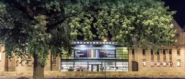 Dieses Bild zeigt ein Gebäude, auf dem ein Plakat zur Internationalen Kunst aufgehängt ist.