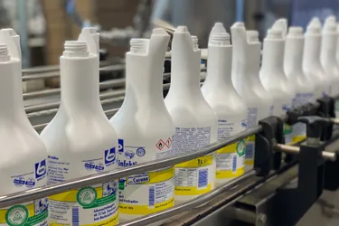 Dieses Bild zeigt viele gleiche Flaschen auf einem Laufband. Die Flaschen sind weiß und undurchsichtig.