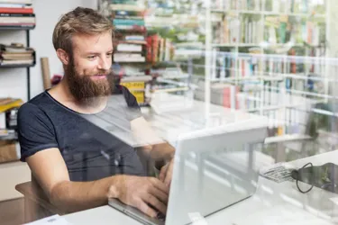 Im Home Office kann Strom gespart werden, indem möglichst viel Tageslicht genutzt wird. Das Bild zeigt einen jungen Mann in seinem vom Tageslicht durchfluteten Home Office.