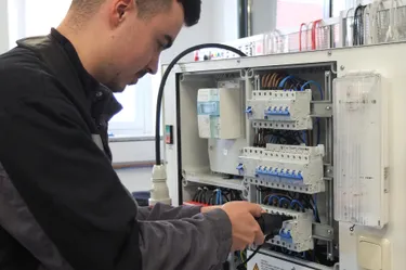 Dieses Bild zeigt den Auszubildenden Julius Heidmann, einen Elektroniker, der an einem Stromkasten tätig ist.