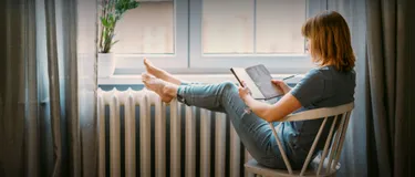 Fünf spannende Fakten zur Fernwärme: Das Bild zeigt eine junge Frau, sitzend auf einem Stuhl mit einem Notizblock in der Hand.