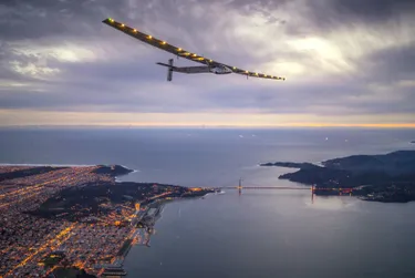 Solarenergie-Fakten: Einsamer Rekord - Alleinflug im Solarflieger. Das Bild zeigt den Solar Impulse 2 fliegend über einer Küste bei Dämmerung. 