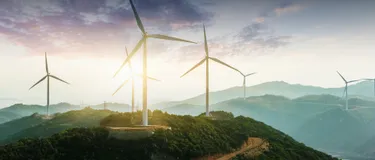 Fünf phänomenale Fakten über Windenergie: Das Bild zeigt mehrere Windräder in bergiger Landschaft bei Sonnenuntergang.