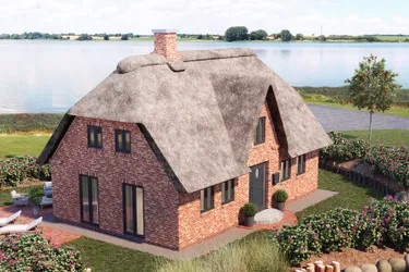 Einfamilienhaus. Dieses Bild zeigt ein Haus mit Reetdach umgeben von der Natur, in der Nähe eines großen Sees.