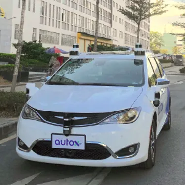 Robotertaxi: Das Bild zeigt ein Robotertaxi der Firma AutoX vor einem großen Gebäude.