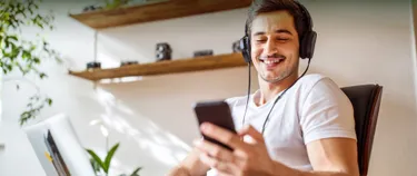 Junger Mann mit Kopfhörern schaut auf sein Handy