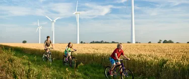 Kinder radeln vor einem Feld mit Windenergieanlagen