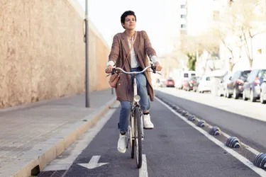 Junge Frau fährt auf einer Straße mit ihrem Fahrrad