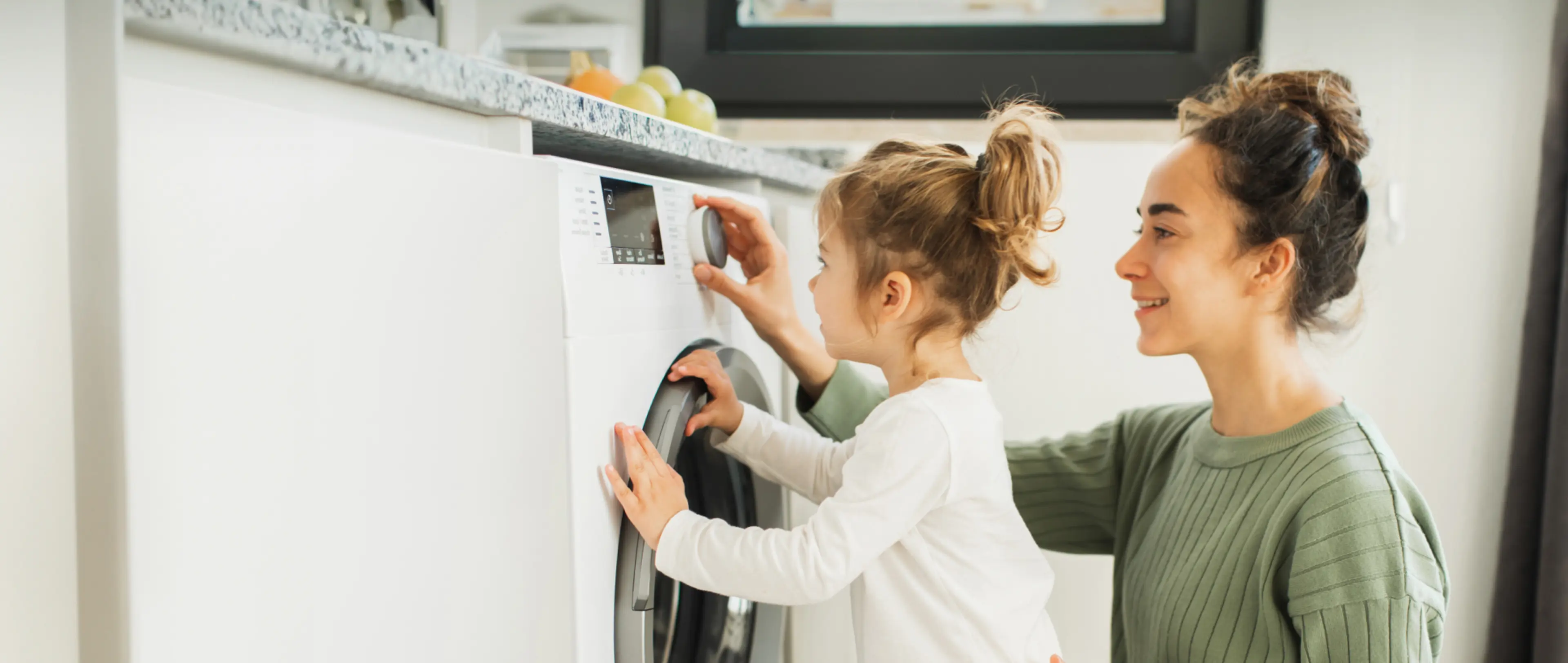 Mutter und Kind vor einer Waschmaschine