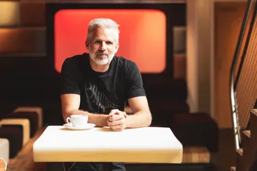 Erfahrung mit Photovoltaik. Dieses Bild zeigt einen Mann, der an einem Tisch sitzt, auf dem eine Tasse steht. Seine Hände hat er ineinander gefaltet.