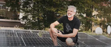 Vorreiter: Photovoltaik. Dieses Bild zeigt einen Mann, der auf einem Dach hockt, auf dem eine Photovoltaikanlage installiert ist.