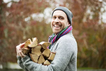 Heizen mit Holz ist weitgehend klimaneutral, wenn das Holz aus regionalen Wäldern kommt. Das Bild zeigt einen jungen Mann, der gehacktes Holz in den Armen hält.