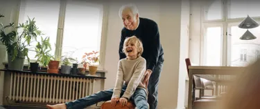 Älterer Mann und kleiner Junge lachen. Im Hintergrund ist eine Heizung.