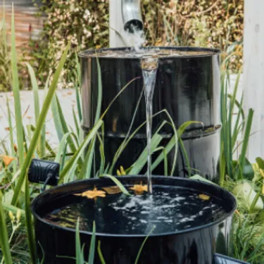 Wer sein eigenes Regenwasser nutzt, spart Wasser aus der Leitung. Das Bild zeigt eine Regentonne voller Regenwasser.
