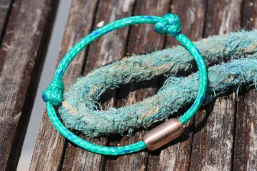Das Bild zeigt ein Armband, hergestellt aus treibenden Geisternetzen aus dem Meer.