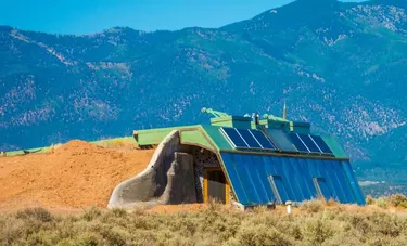 Wohnkonzepte der Zukunft: Das Bild zeigt ein Earthship Wohngebäude vor einer Berglandschaft.