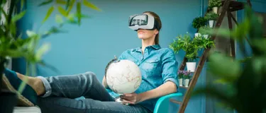 Wohnkonzepte der Zukunft: Das Bild zeigt eine Frau zuhause im Sessel mit einer Virtual Reality Brille auf dem Kopf.