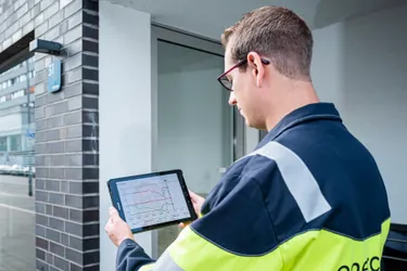 Dieses Bild zeigt einen Servicetechniker, der in der Hand ein Tablet hält, um Daten abzufragen.