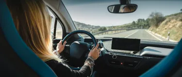 Pendlerpauschale 2021: E-Auto vs. Verbrenner. Das Bild zeigt eine Frau am Steuer eines Elektroautos.