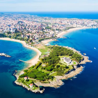 Santander. Dieses Bild zeigt einen Ausschnitt von Santander in Spanien, aus der Vogelperspektive. Zu sehen ist das Meer, sowie eine Küstenstadt mit viel Natur.