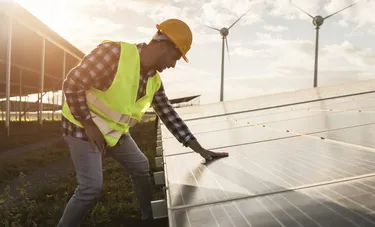 Wind-und Solarpark. Dieses Bild zeigt ein Wind- und Solarpark, der Strom produziert. Ein Mitarbeiter kontrolliert hier gerade eine Solarplatte.