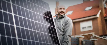 Die eigene Solaranlage: Das Bild zeigt einen Monteur mit einem Solarpanel in einer Wohnsiedlung