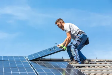 Solarmontage: Das Bild zeigt einen Monteur, der gerade ein Solarpanel auf einem Hausdach anbringt