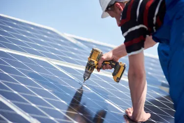 Solarmontage: Das Bild zeigt einen Monteur, der die Solarpanels mit Schrauben fixiert