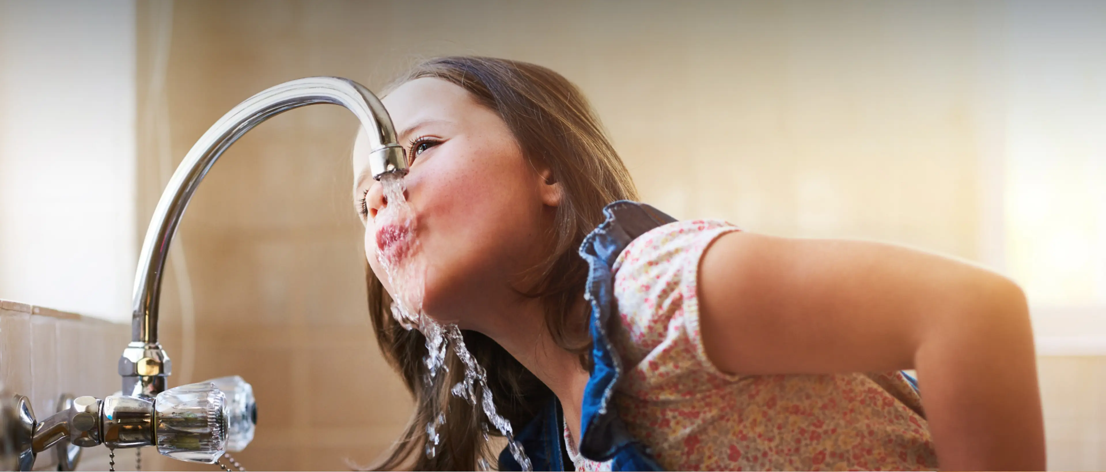 Lebenselixier Wasser Lebenselixier Wasser. Dieses Bild zeigt ein Mädchen, welches aus dem Wasserhahn Wasser trinkt.
