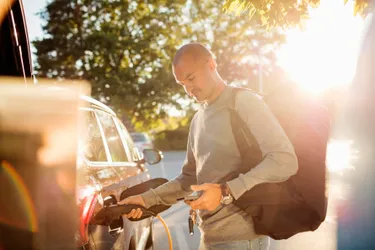 Dieses Bild zeigt einen Mann, der gerade sein Elektroauto lädt.