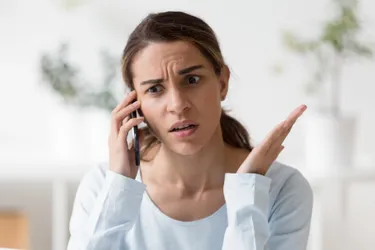 Trickbetrug an Telefon und Haustür: So schützen Sie sich. Das Bild zeigt eine Frau am Telefon, die verängstigt und verwirrt aussieht. 