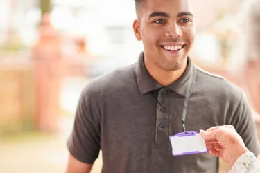 Mitarbeiter sollten sich mit offiziellen Ausweisdokumenten ausweisen können. Dieses Bild zeigt, wie eine Person den Mitarbeiterausweis eines Mannes anschaut.