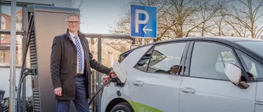 E-Mobilität. Dieses Bild zeigt einen Mann, der gerade dabei ist, sein Elektroauto aufzuladen.