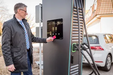 GDA-Ladepunkte. Dieses Bild zeigt einen Mann, der an einer Ladesäule steht, um sein Elektroauto zu laden.