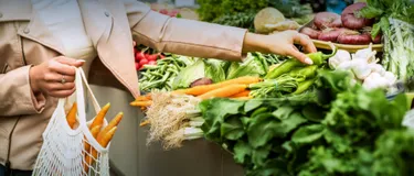 Grüner leben: Was bedeutet Klimaneutralität? Das Bild zeigt eine Frau, die Obst und Gemüse in einem Bio-Supermarkt in einen Leinenbeutel legt.