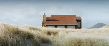 Nachhaltig reisen: klimafreundliche Urlaubstipps. Das Bild zeigt ein Haus in den Dünen.